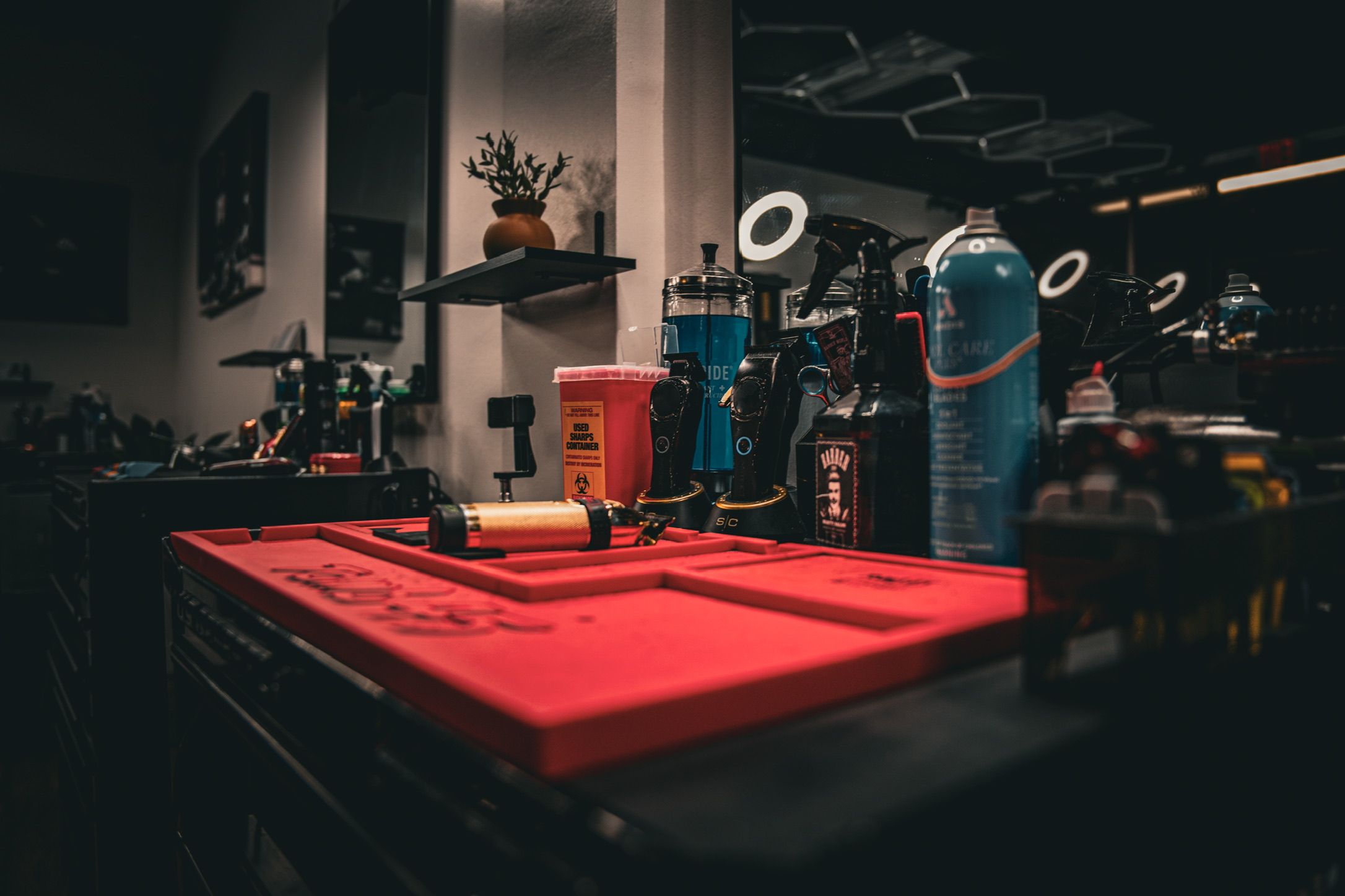 Dark barbershop counter with red mat, hair products and professional equipment.