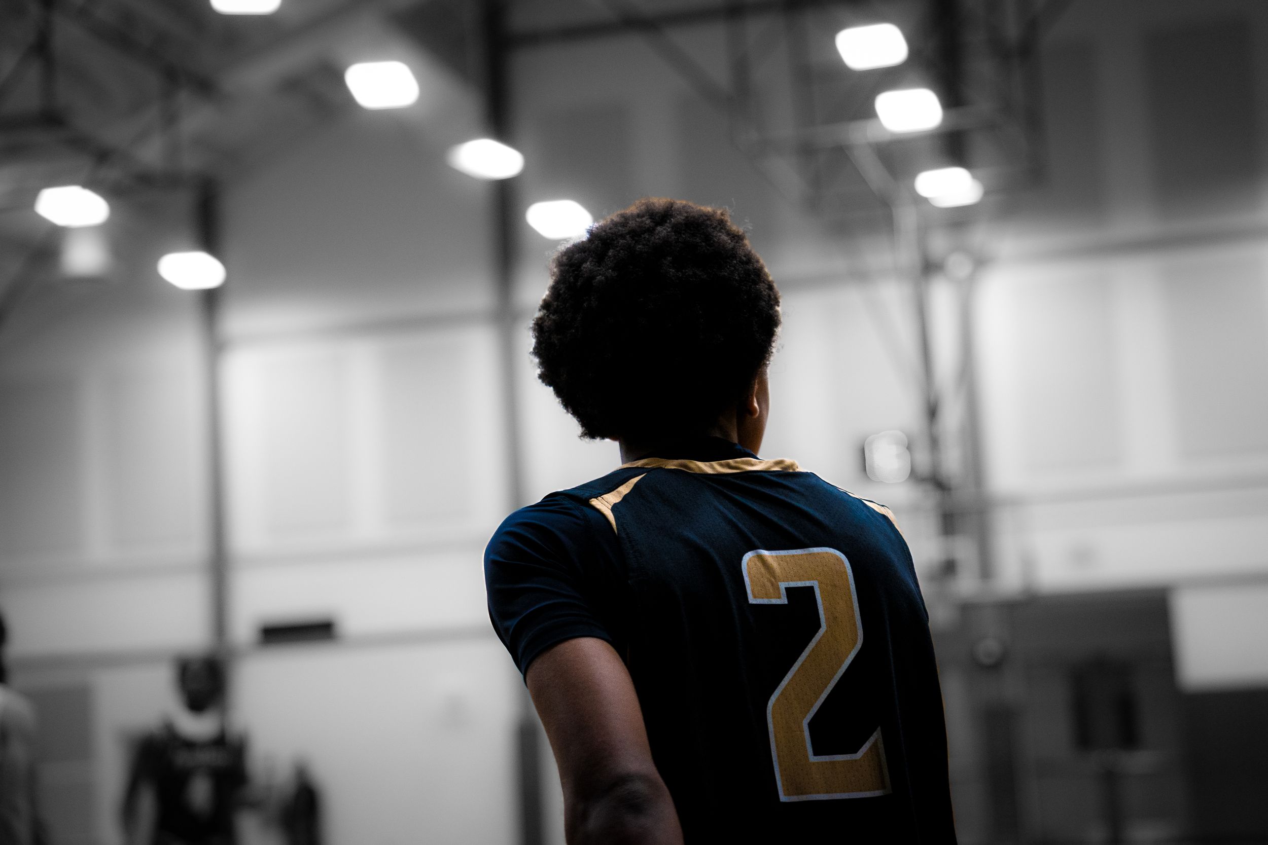 Basketball player wearing navy blue jersey number 2 standing in indoor gym.