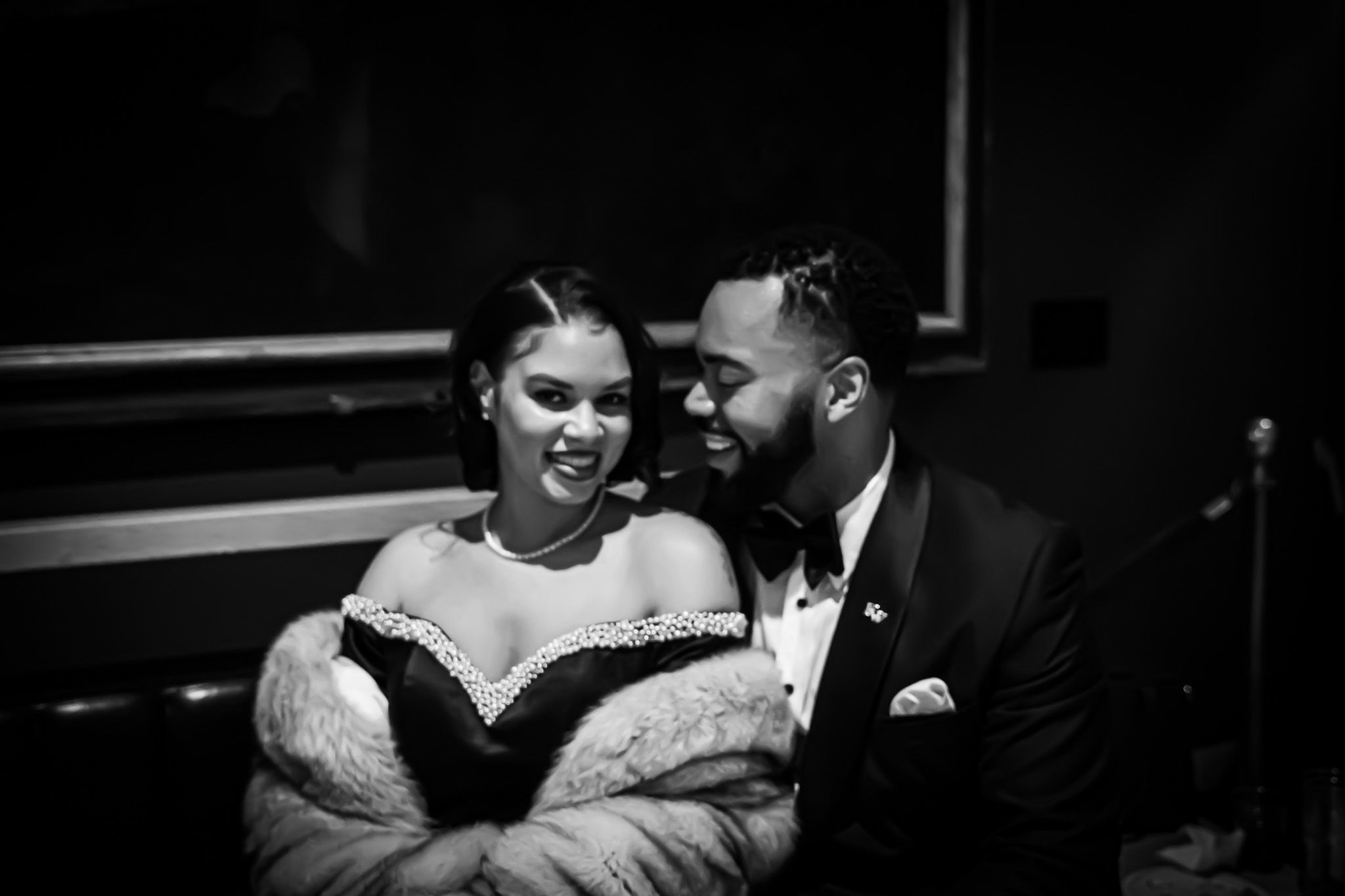 Black and white photo of a couple sharing a joyful moment at a formal event.