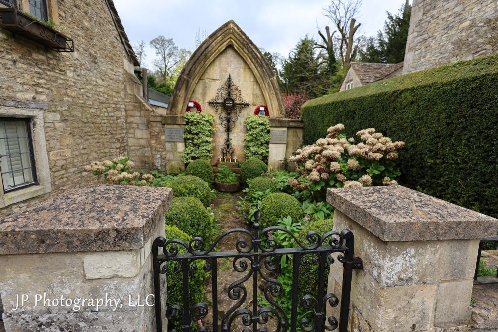 Stone garden path with ornate iron gates and traditional English cottage architecture.