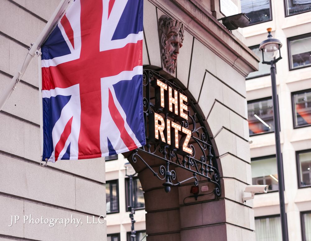 British Union Jack flags displayed on a building exterior with The Ritz signage.