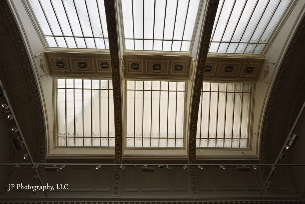 Long horizontal view of illuminated museum skylights with geometric patterns.