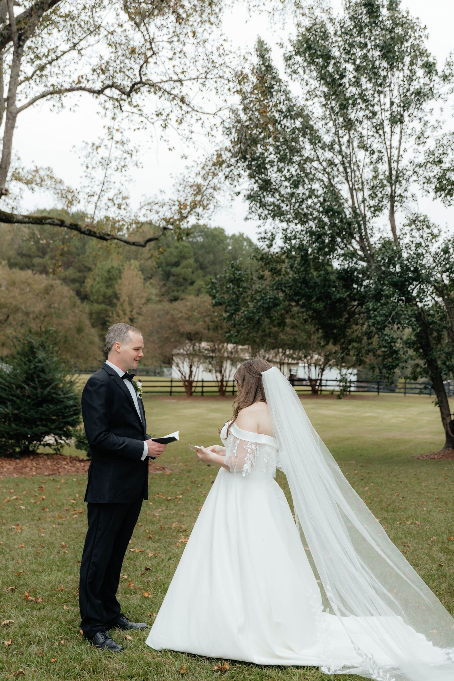 Wedding first look and reading of vows captured outdoors with trees in background.