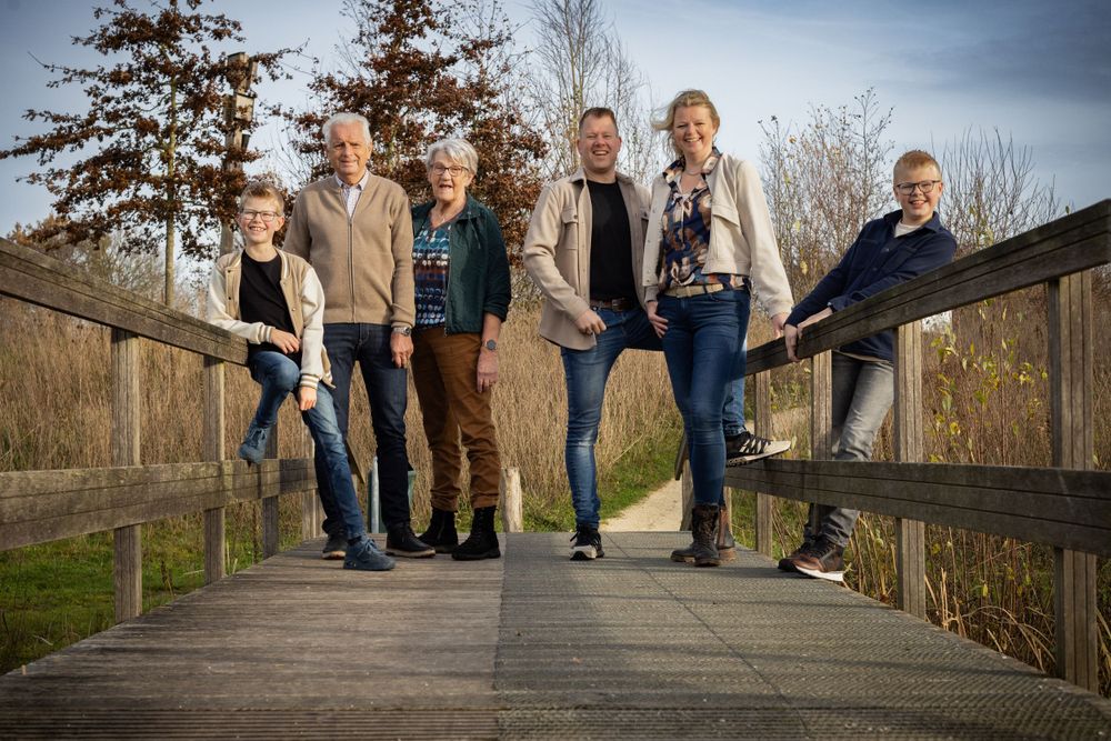 Family members pose together on wooden bridge in natural setting.