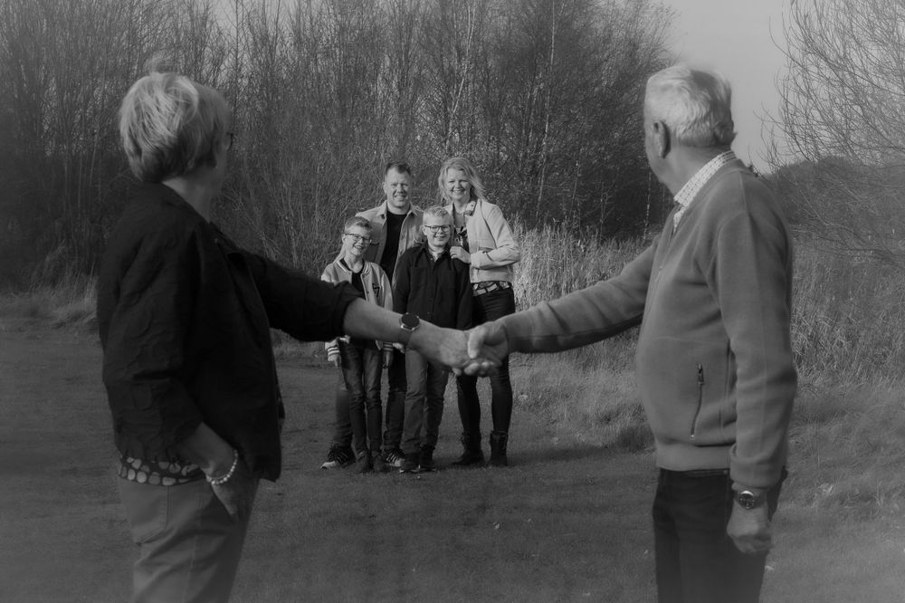 Black and white photo of family members playing a game outdoors.