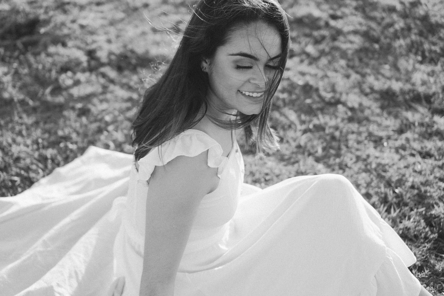 Mulher sorri ao ser fotografada com seu vestido branco © Clara e Matheus Fotógrafos de Casamentos