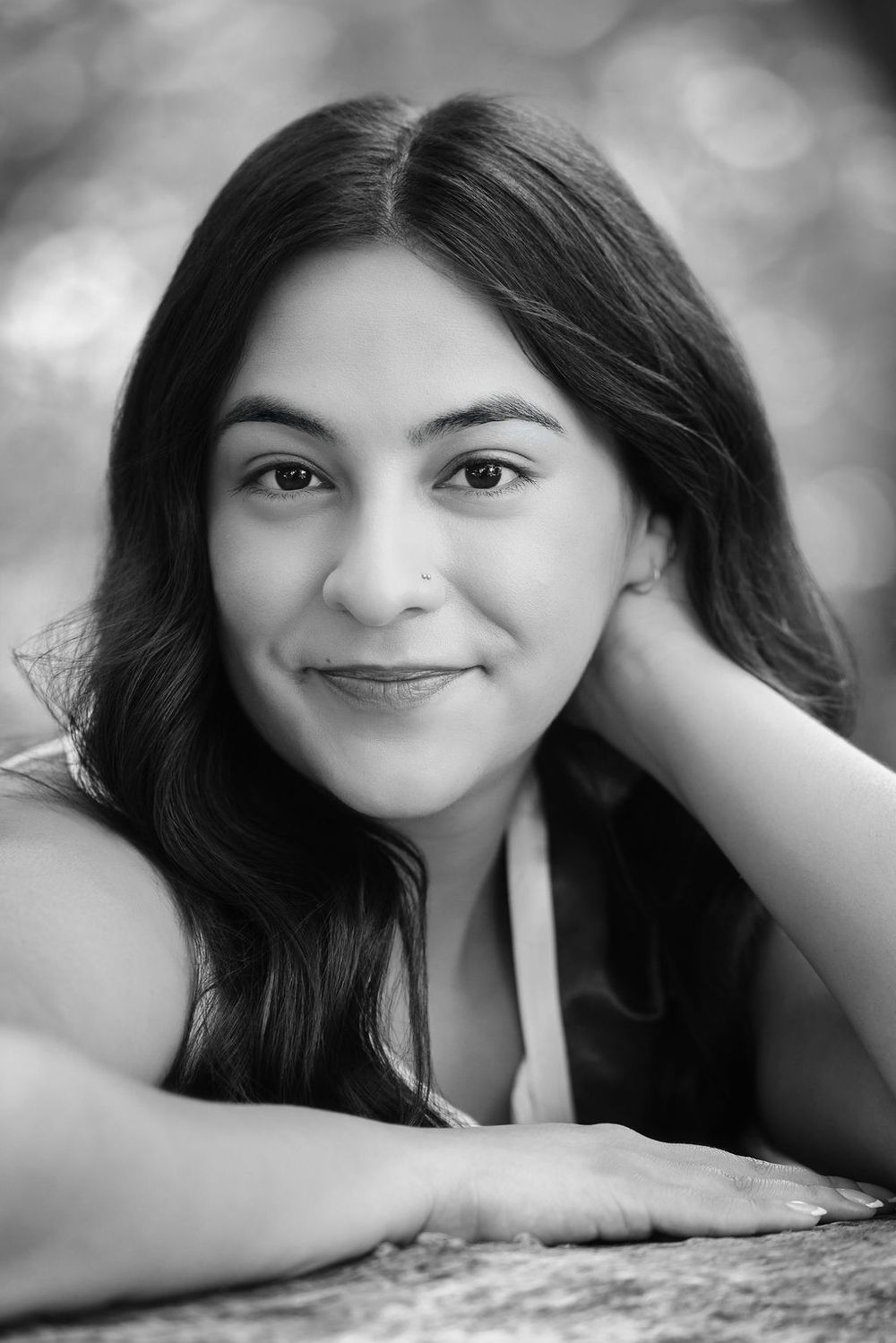 Black and white portrait of a young woman with dark hair resting her head on her hand.