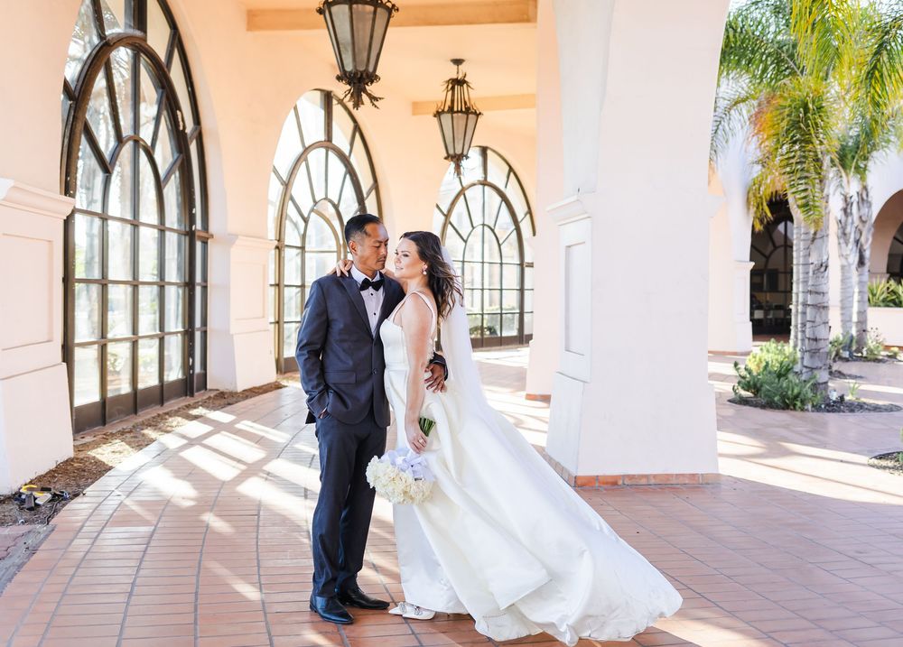 Elegant couple in formal wedding attire standing under arched walkway at Santa Barbara Waterfront Hilton.