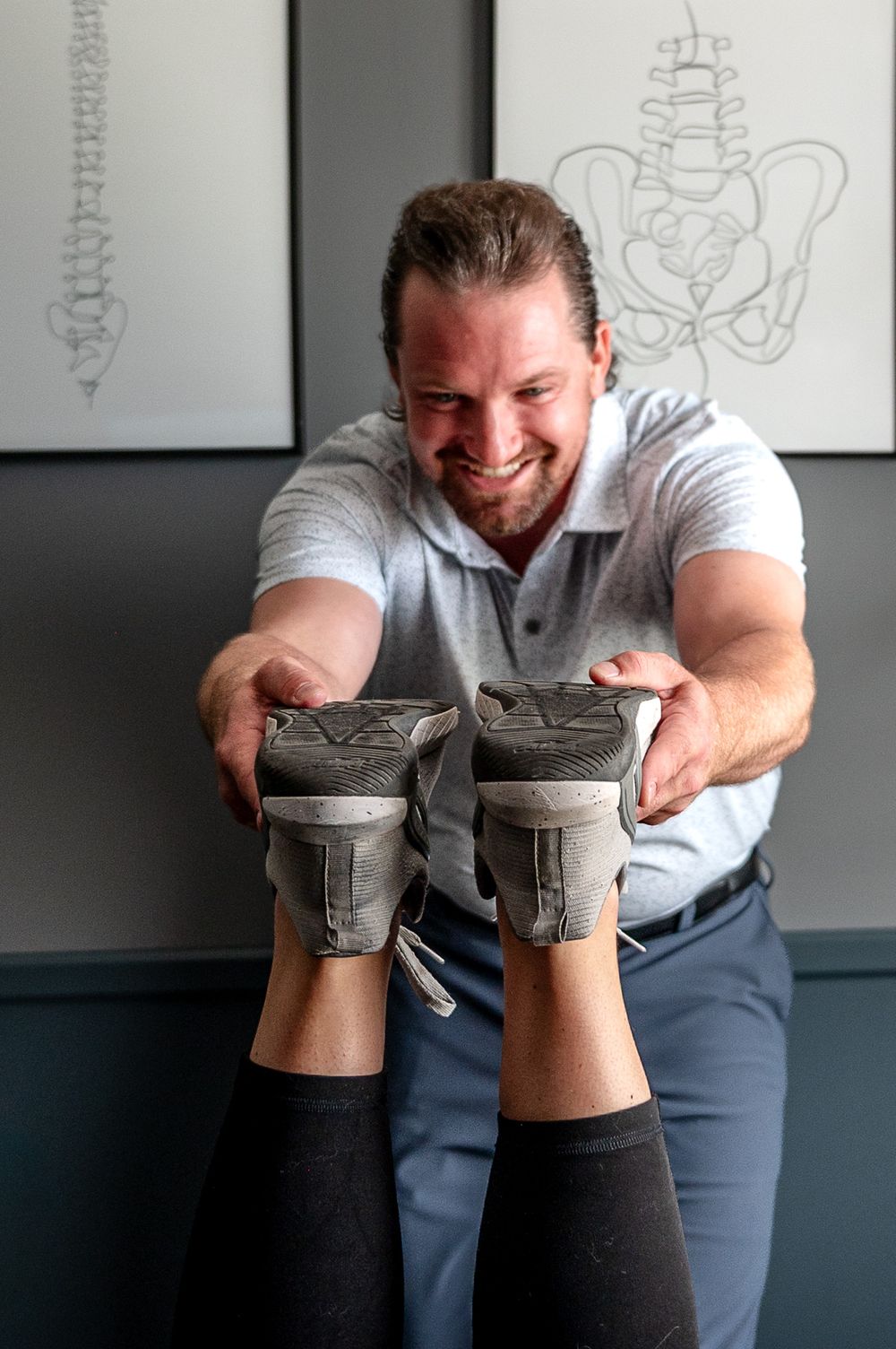 Chiropractor smiling while performing foot adjustment on patient in clinical treatment room.