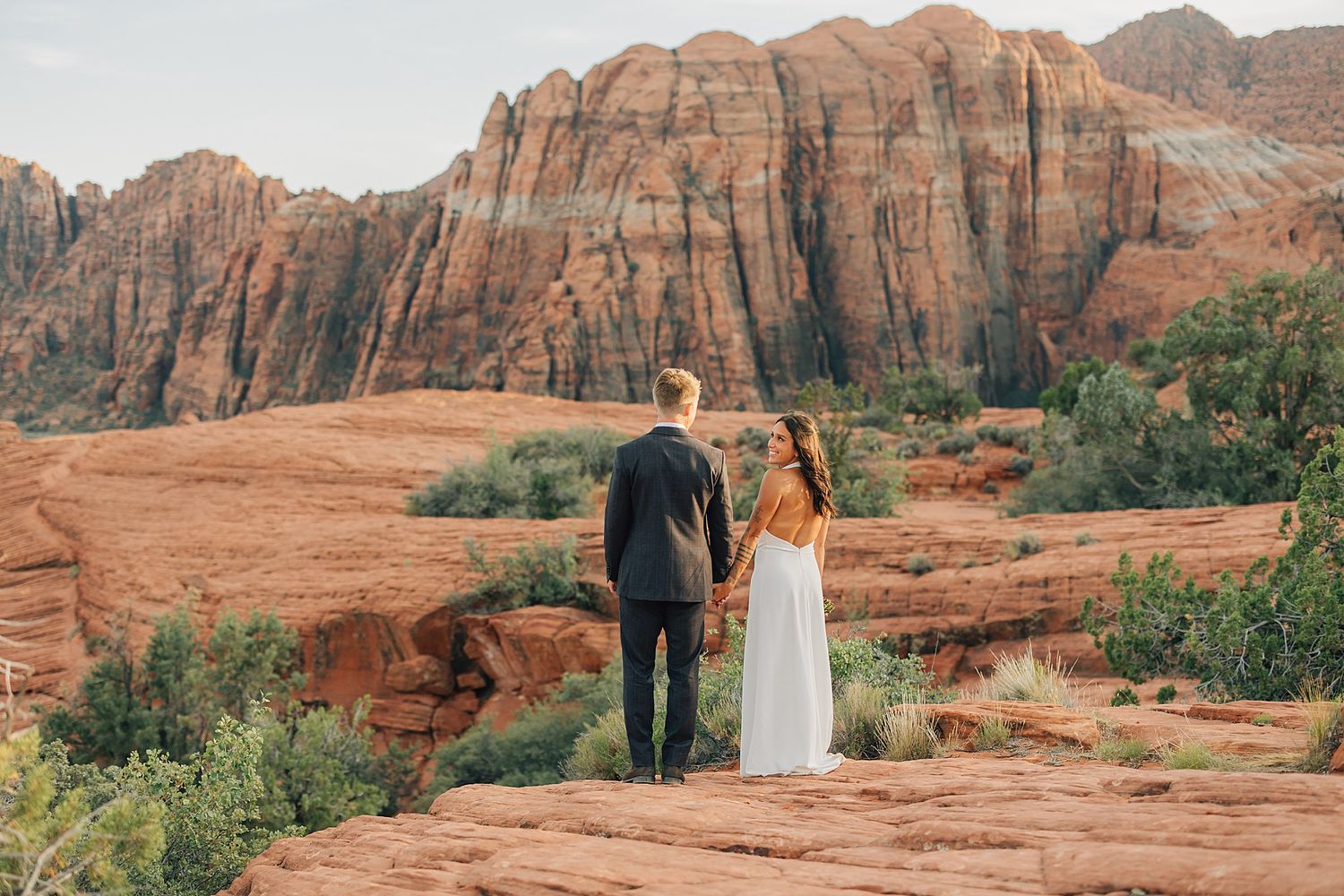 Couple holding hands gazing at red rock formations at Snow Canyon State Park desert elopement.