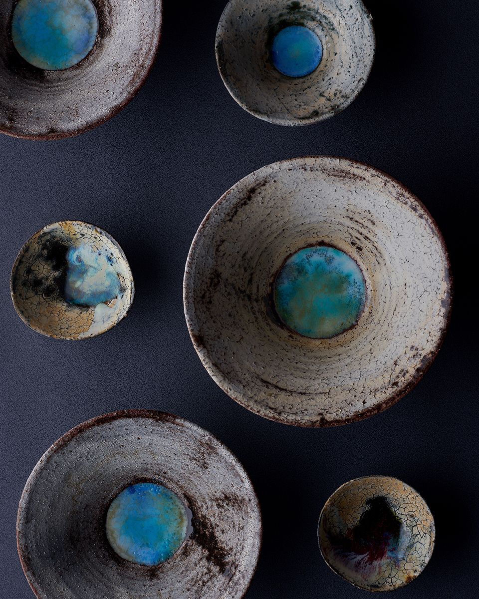 Rustic handmade ceramic bowls with turquoise glaze centers on dark background, showcasing artisan pottery craftsmanship.