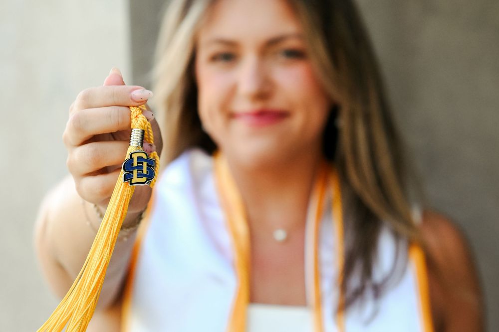 South Dakota State University graduate holding a SDSU logo from graduation day.