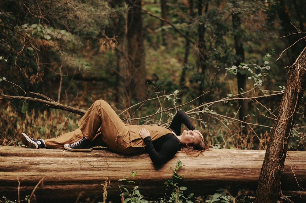 Senior girl portrait in lush green outdoor setting with deep forest tones, warm edits and a timeless filmy feel.
