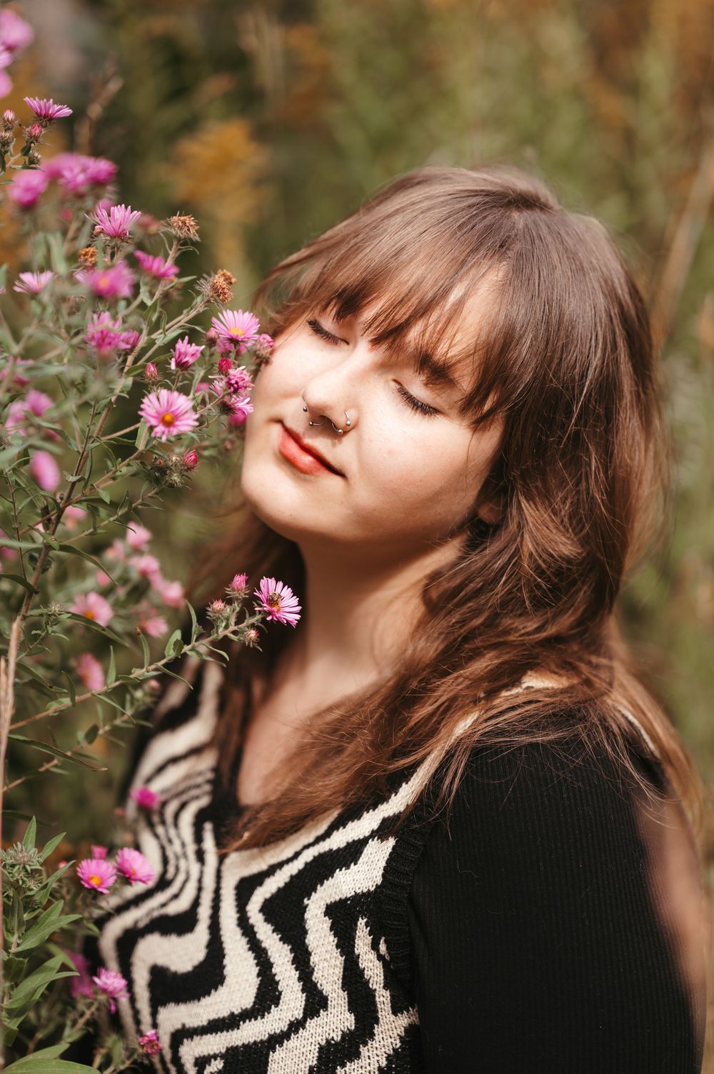 Timeless senior portrait of a girl outdoors with rich greenery, warm tones, flowers and a soft filmy edit.