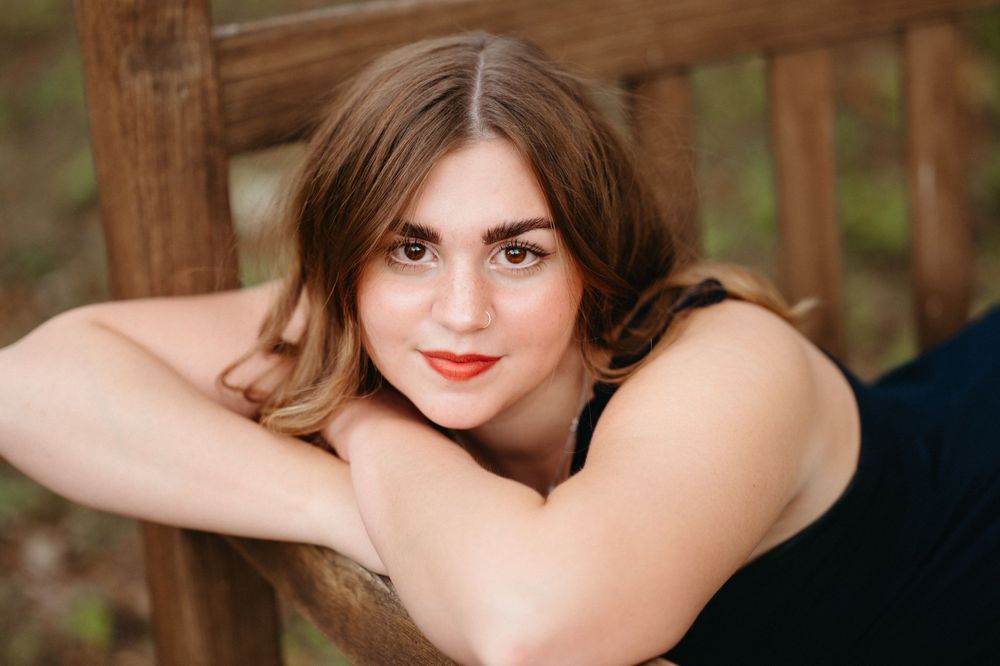 Brookings SD senior photographer creating timeless outdoor portraits with deep green hues and warm filmy edits.
