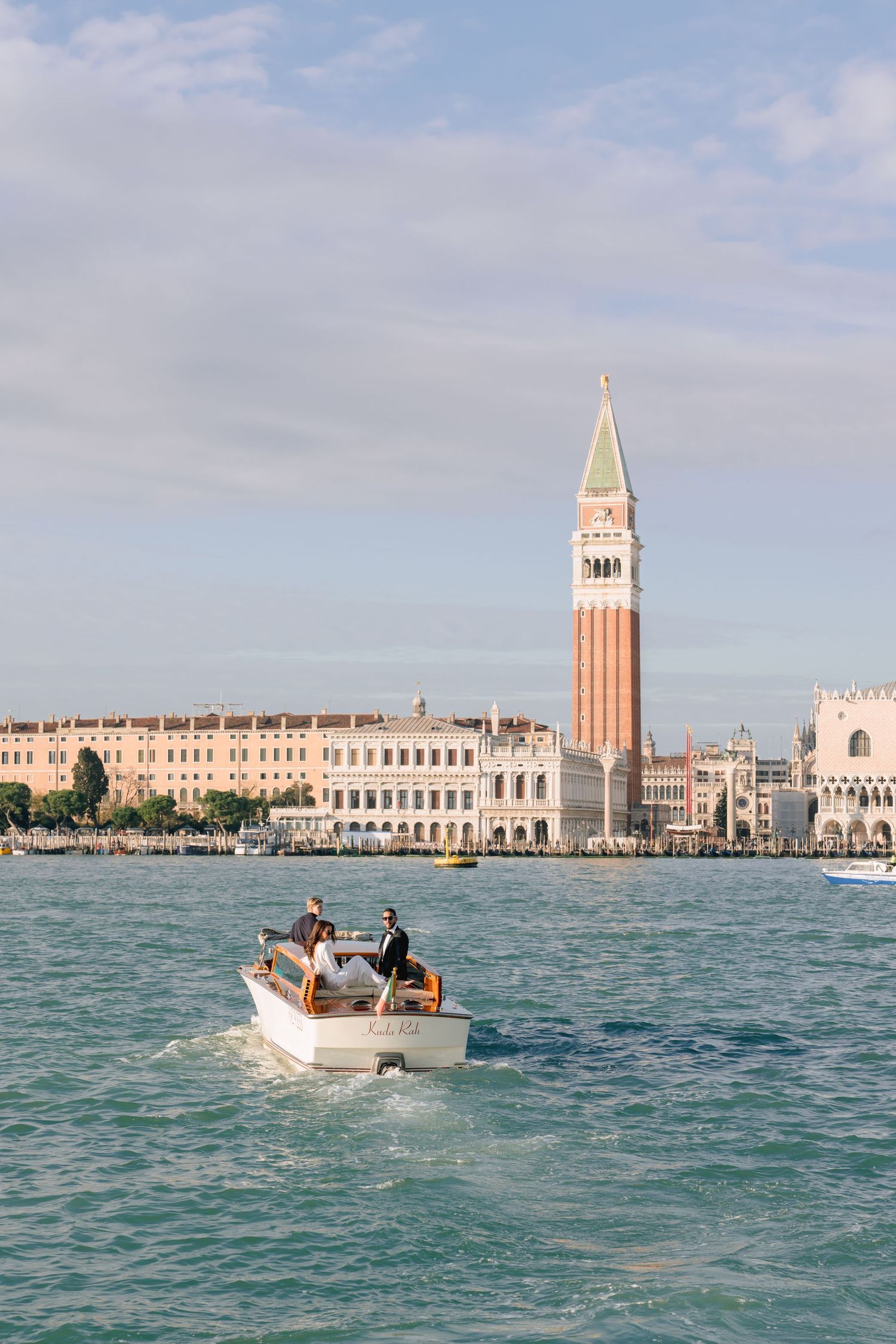 Couple toasting champagne on a boat in Venice's Grand Canal with Santa Maria della Salute basilica backdrop.
