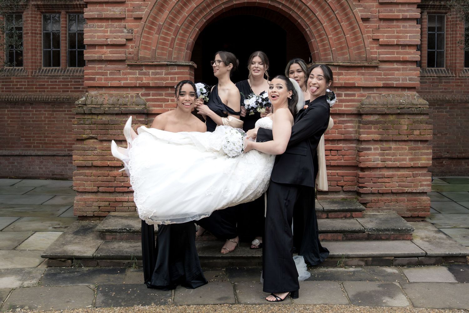 A romantic wedding couple embraces under a flowing veil in a lush green garden setting.