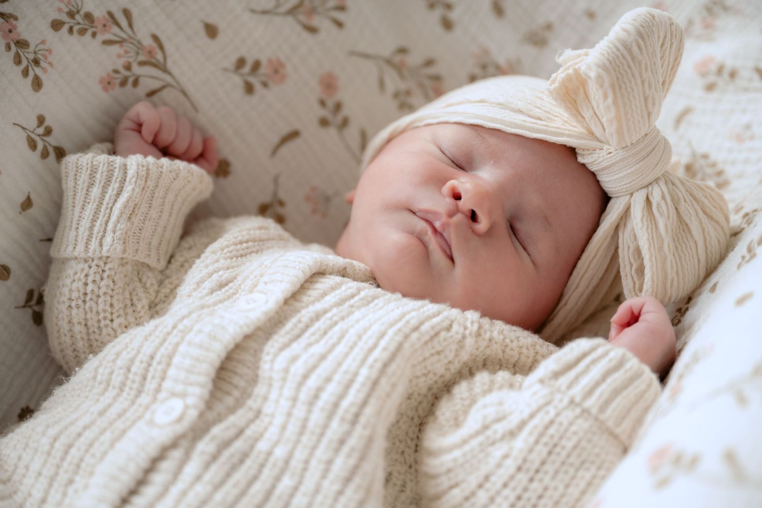 newborn baby wearing knit sweater and big linen bow fast asleep during in-studio lifestyle newborn session in stillwater, mn