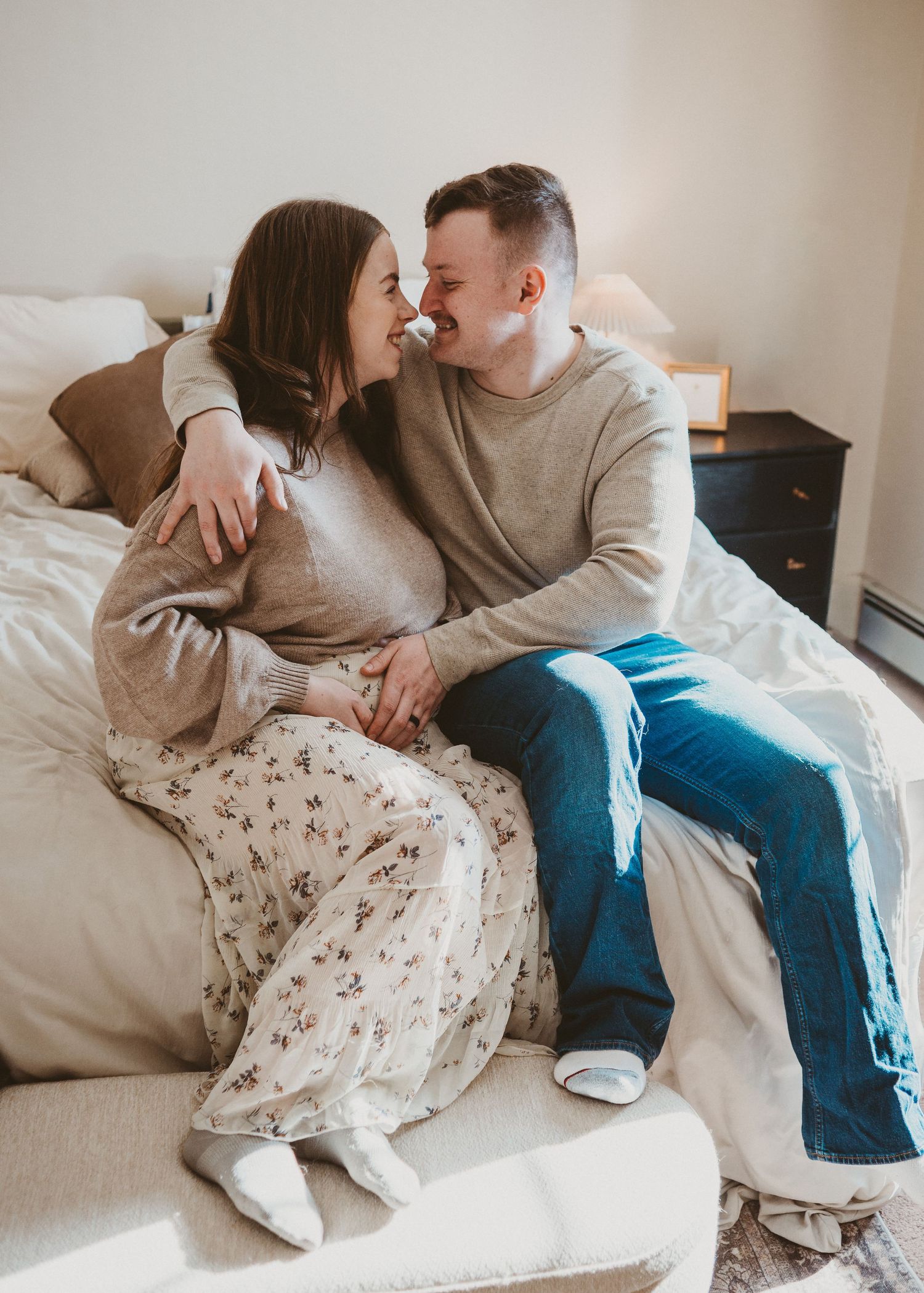 Expecting couple sitting together on a couch at home during a maternity session
