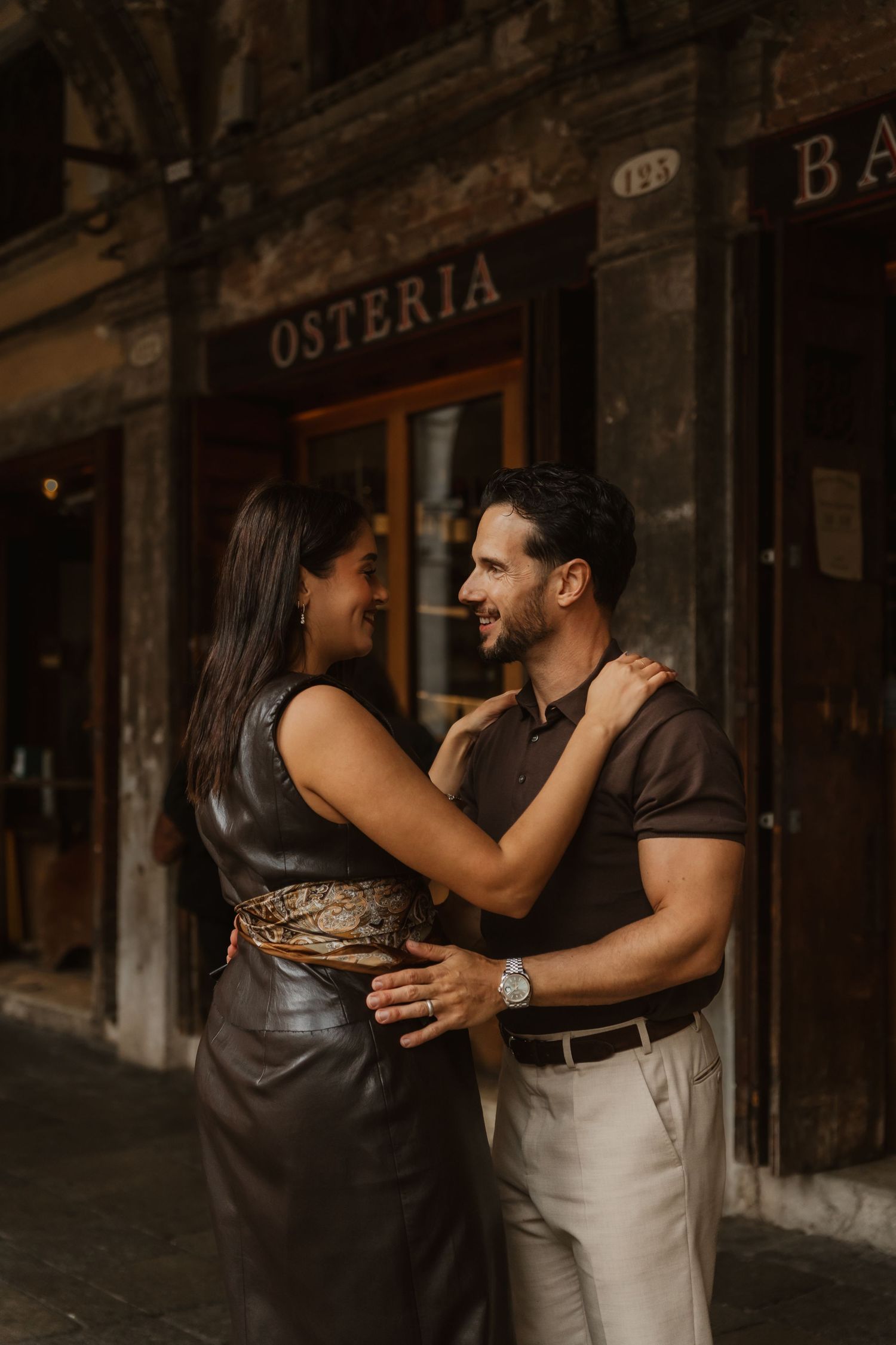 A French couple next to a Bacaro bar in Venice, hugging and enjoying the moment together spontaneously.