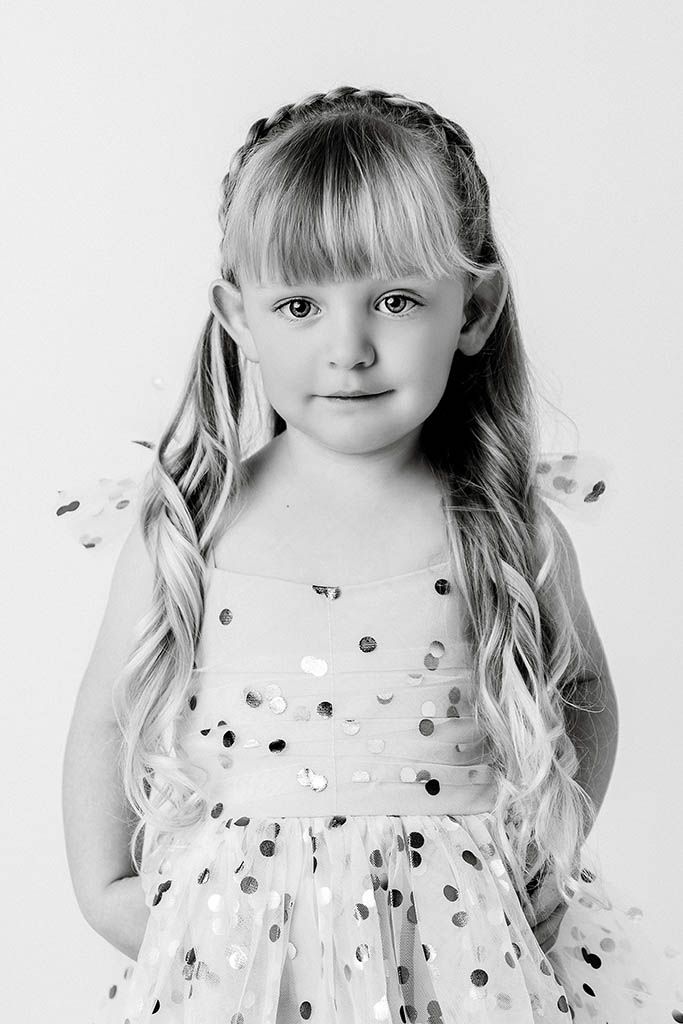 Black and white portrait of a young blonde girl in a sequin dot dress with braided hair.