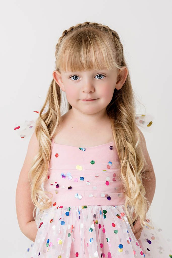 Blonde girl in pink polka dot dress with braided hair smiling at camera by Murrieta child photographer.