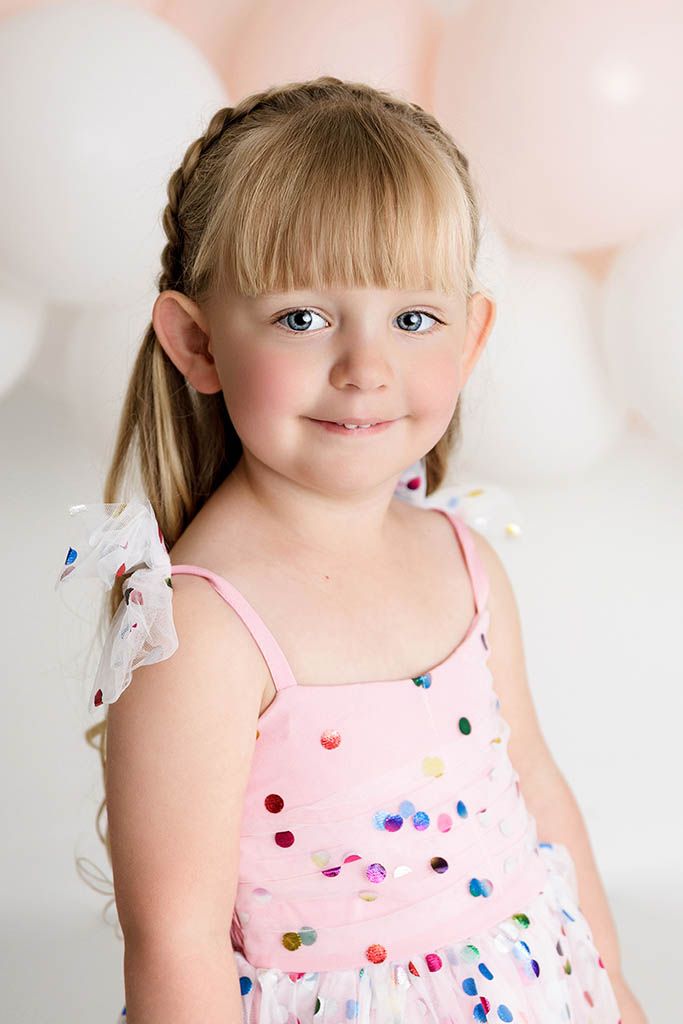 Young blonde girl with blue eyes in a pink sequin confetti dress smiling by Murrieta child photographer.