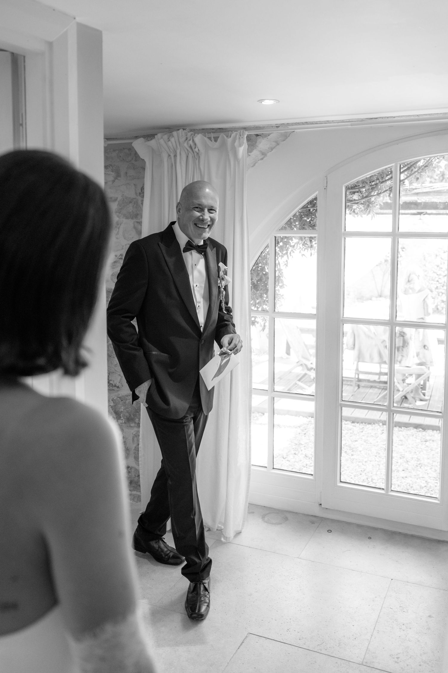 Groom in tuxedo smiling at bride during an emotional first look moment inside an elegant venue.