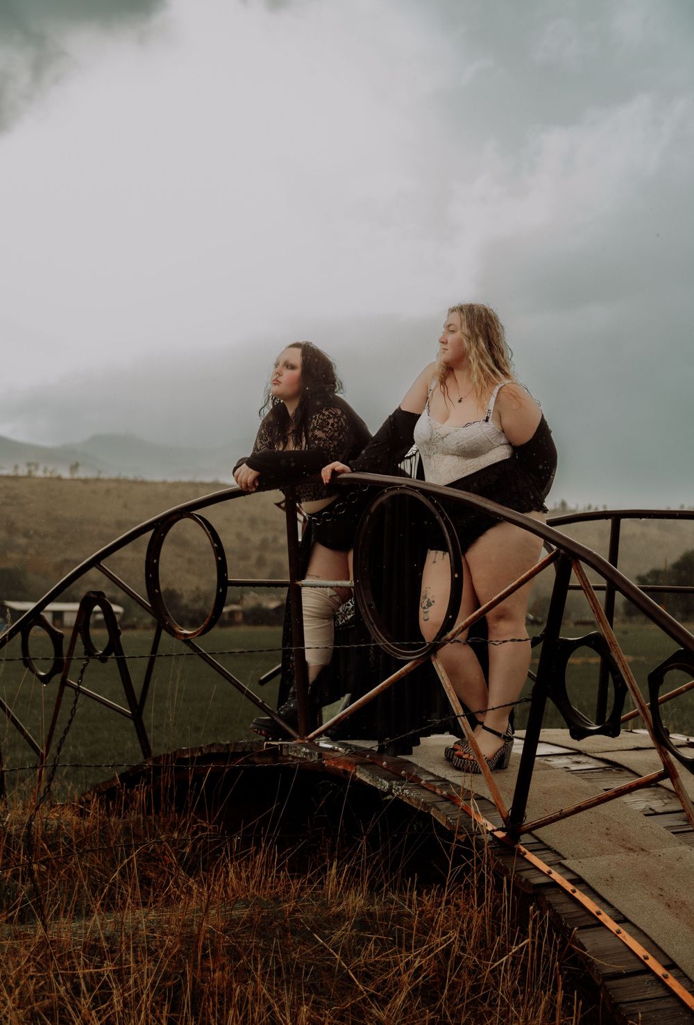 Two women pose on a bridge for dramatic, cinematic, portrait, and modeling photos in Fort Collins, Colorado