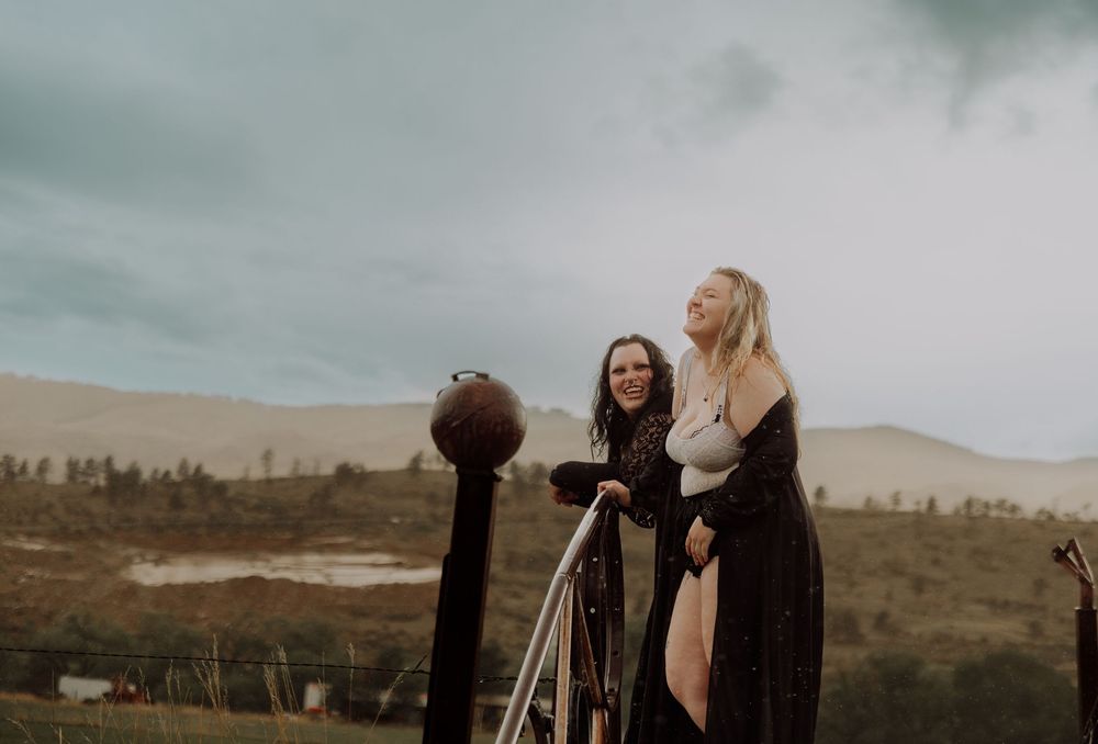 Two women laugh and pose on a bridge for dramatic, cinematic, portrait, and modeling photos in Fort Collins, Colorado