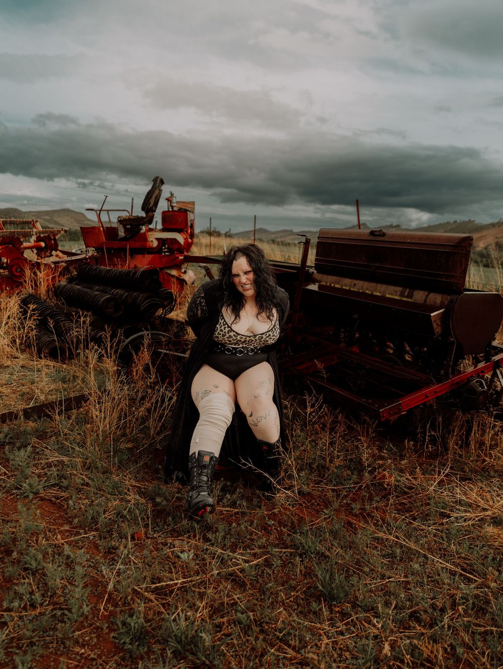 Woman sits and poses in field for dramatic, cinematic, portrait, and modeling photos in Fort Collins, Colorado