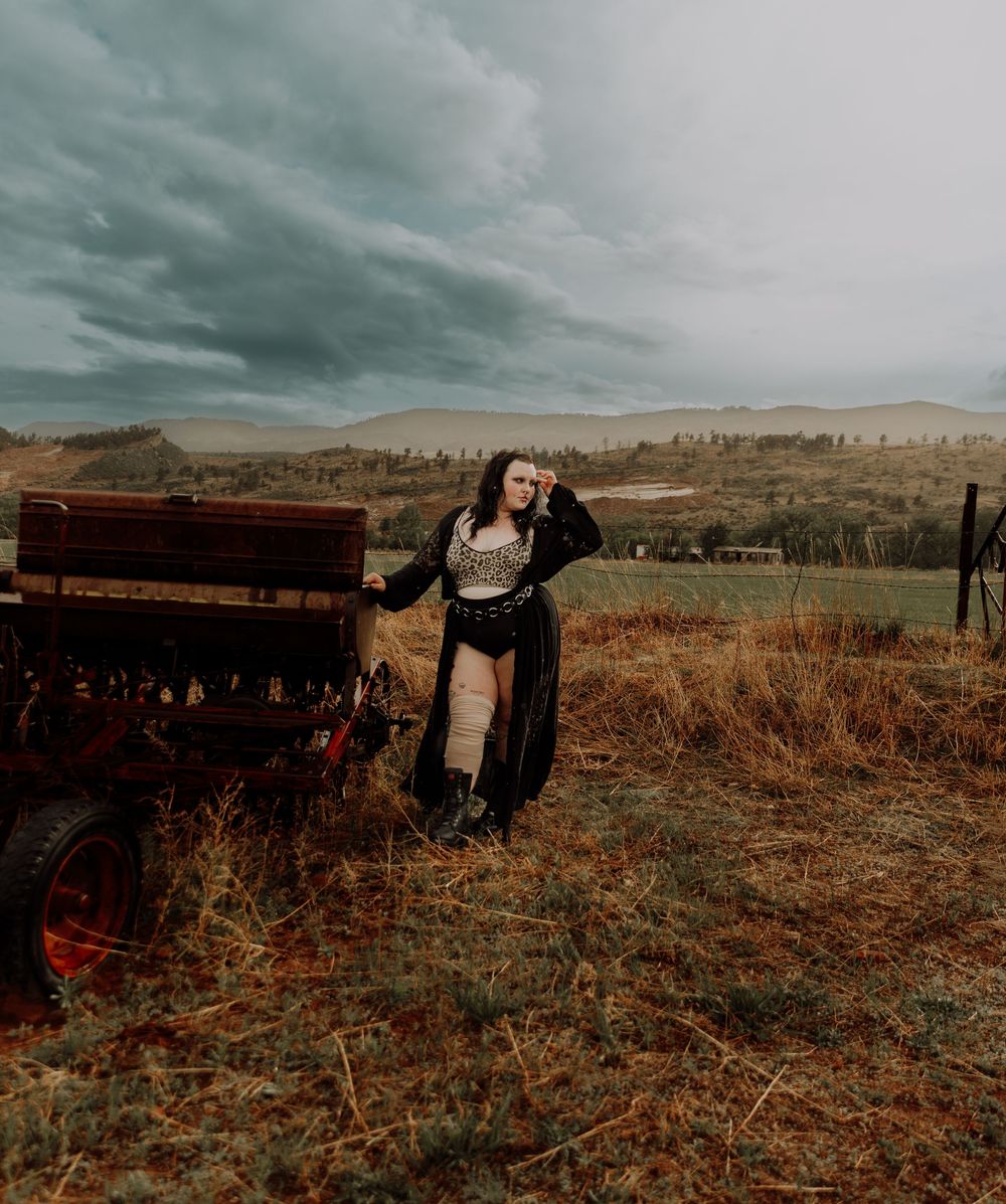 Woman poses in field for dramatic, cinematic, portrait, and modeling photos in Fort Collins, Colorado