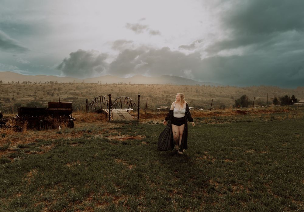 Woman walks and poses in field for dramatic, cinematic, portrait, and modeling photos in Fort Collins, Colorado