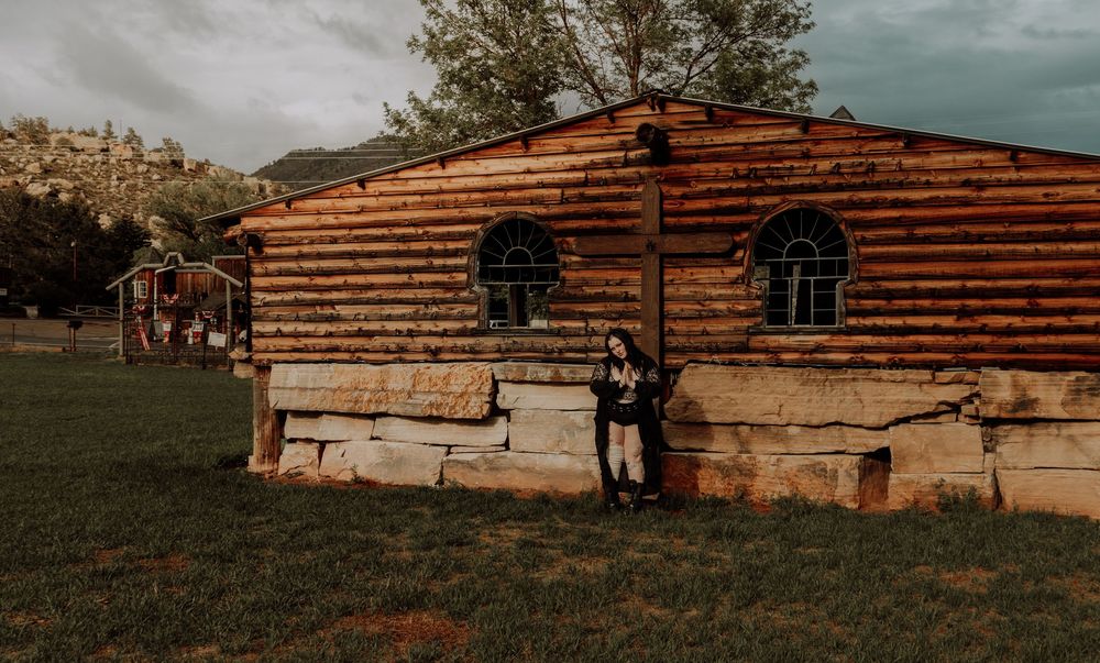 Woman poses in front of old wood church for dramatic, cinematic, portrait, and modeling photos in Fort Collins, Colorado