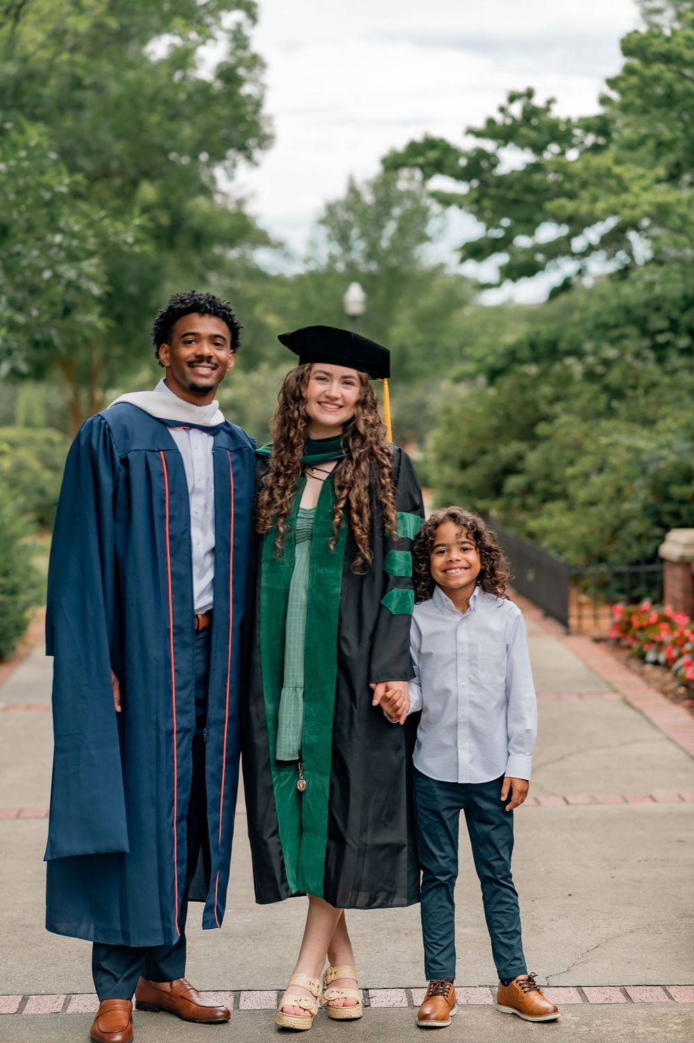 Family of three celebrates graduation at Auburn University, two in academic regalia with a young boy.