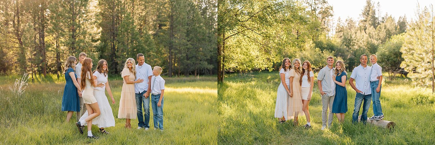 Family posing together in a sunny green meadow surrounded by tall trees, wearing casual summer outfits.