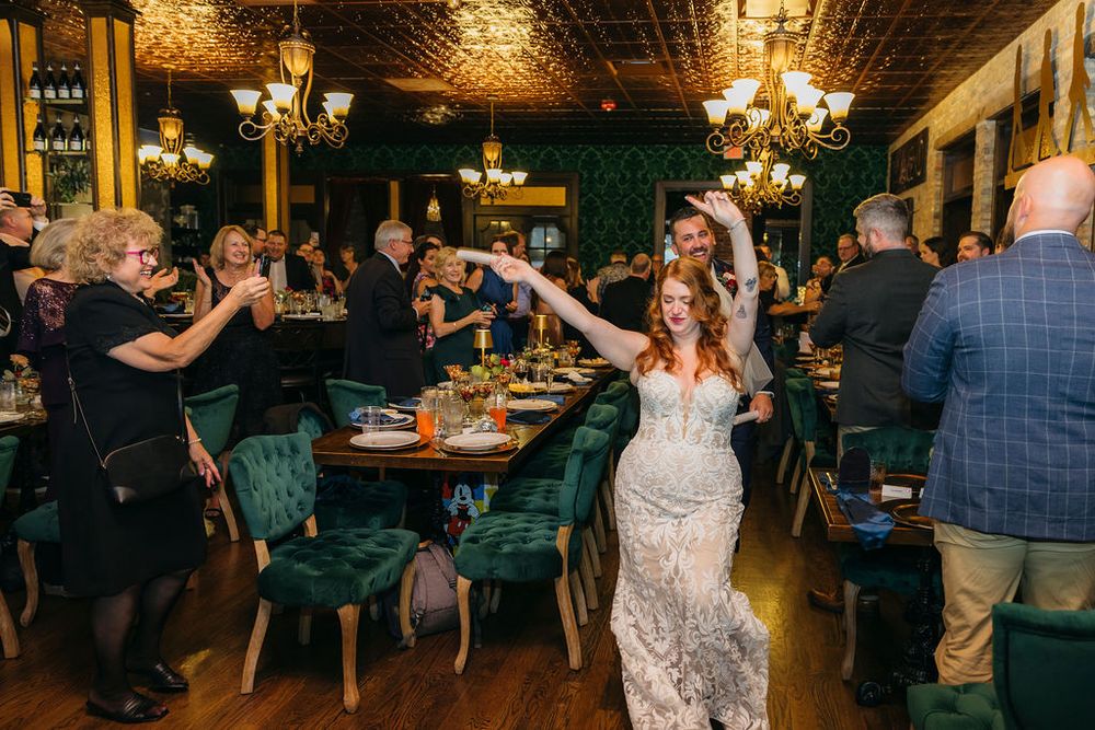 Bride in lace gown dancing joyfully with guests at elegant wedding reception in green velvet decorated venue Arcada Theater in Saint Charles