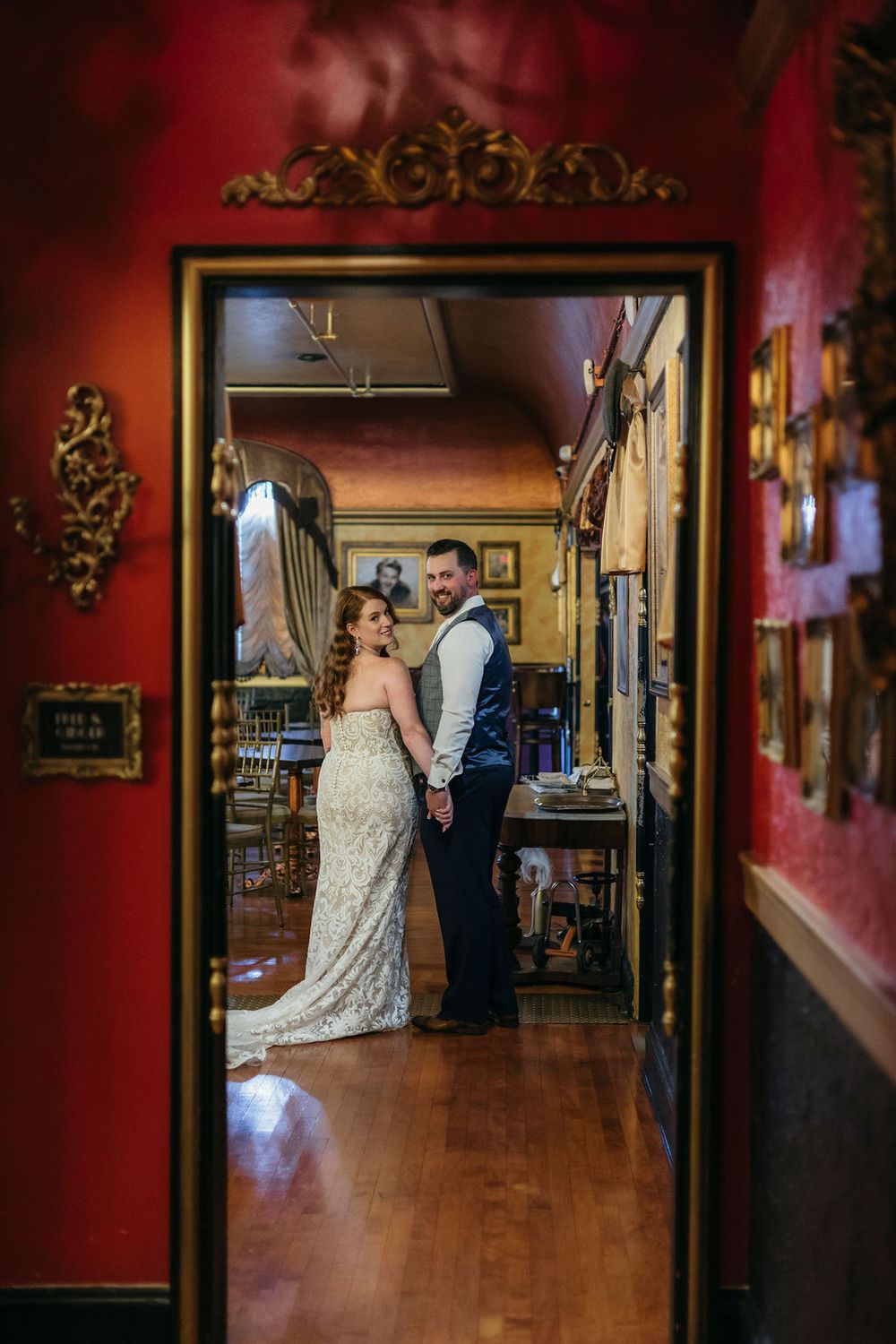 Bride and groom pose romantically in a doorway of an elegant red-walled venue Arcada Theater in Saint Charles, IL