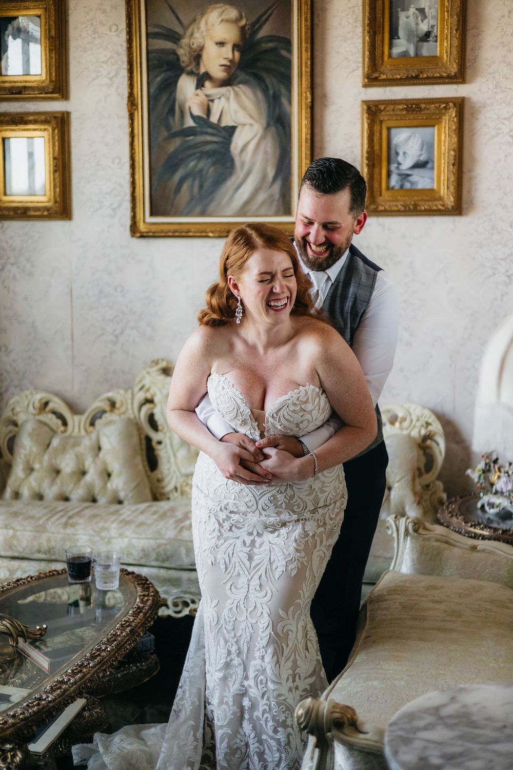 A joyful bride in a lace gown laughs as her groom embraces her in an elegant vintage-styled room of Arcada Theater in Saint Charles, IL