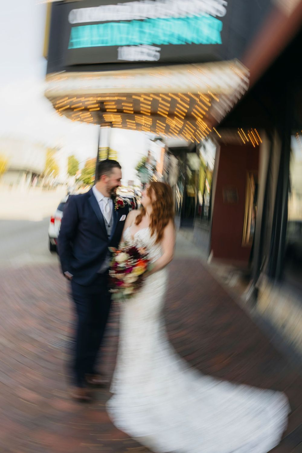 Bride and groom share a romantic moment outside a venue marquee in blurred wedding portrait in front of Arcada Theater in Saint Charles, IL