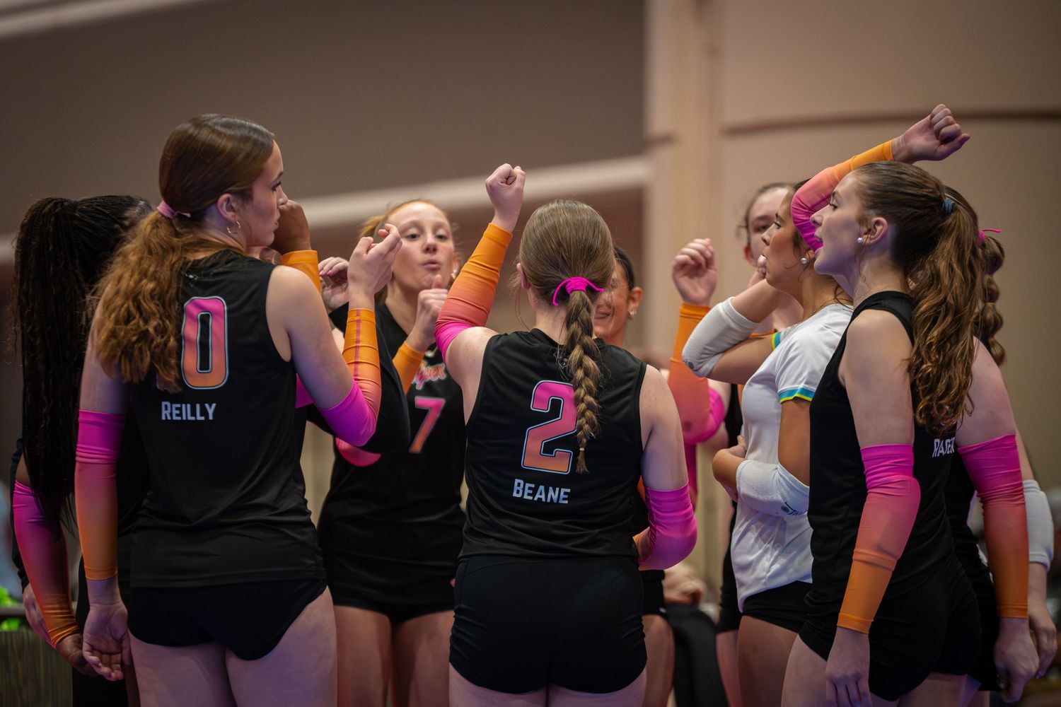 Female volleyball player in red uniform performing a dig during an indoor volleyball match.