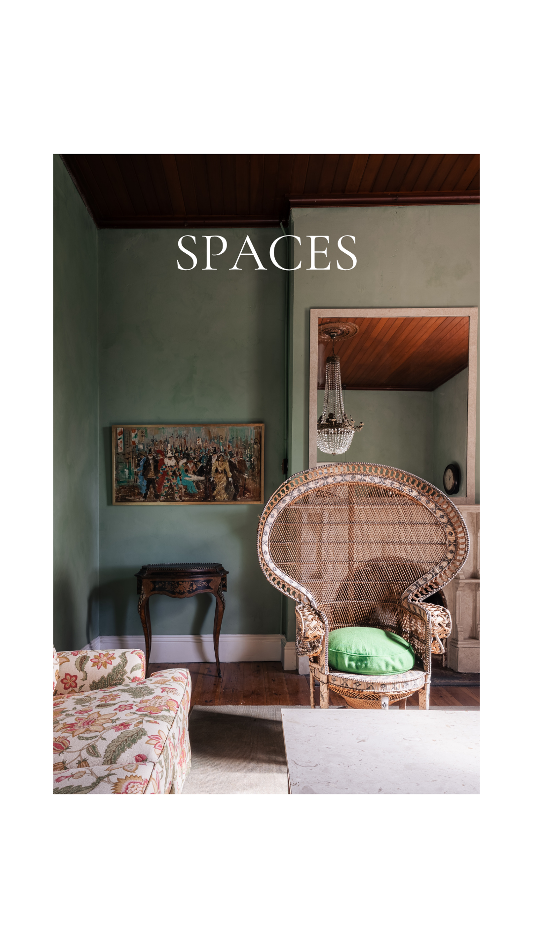 Elegant green-walled living room with rattan peacock chair, floral sofa, and vintage painting labeled SPACES.

Lime au lait atelier