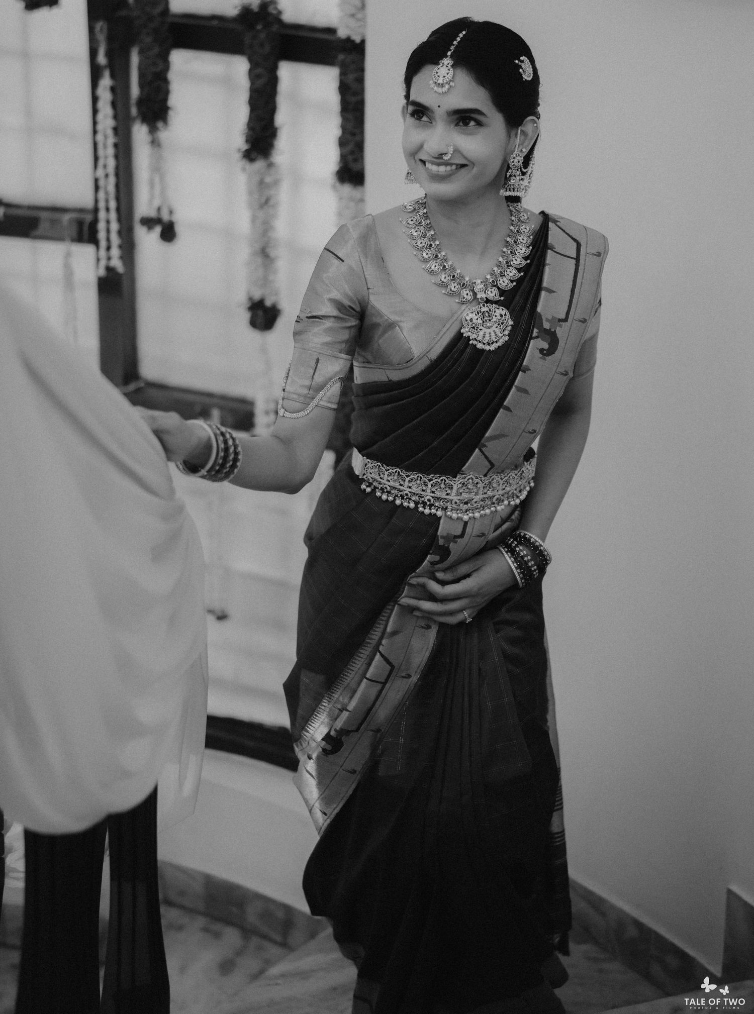 Smiling bride in black silk saree with silver jewelry and maang tikka at traditional South Indian wedding.