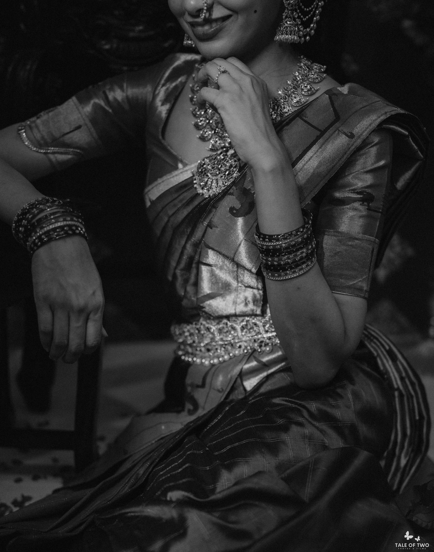 Close-up black and white image of South Indian bride in silk saree showcasing ornate silver jewelry and bangles.