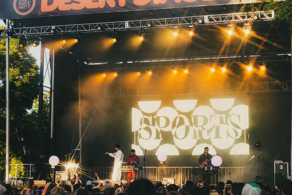 Sports band performing live on stage at Desert Daze music festival with vibrant yellow stage lighting.