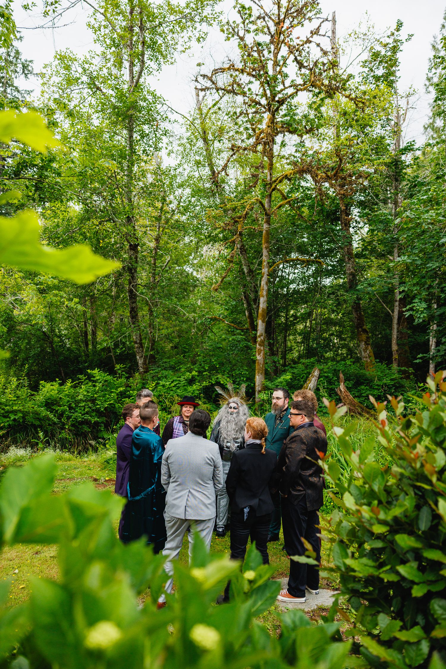 Wedding guests gathered in a lush green forest clearing for an intimate outdoor ceremony.