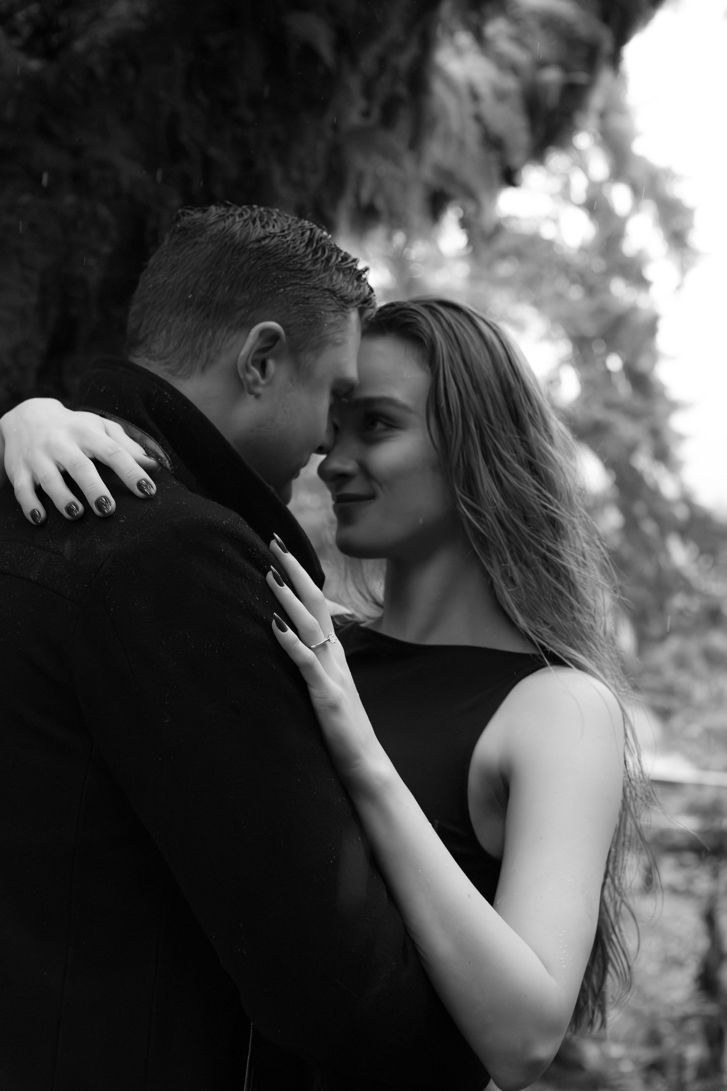 Black and white intimate portrait of couple sharing romantic moment outdoors.