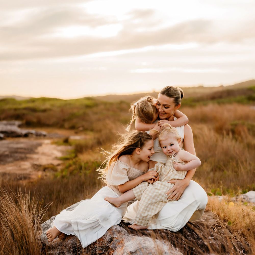 Mother and children snuggle at sunset in Sydney