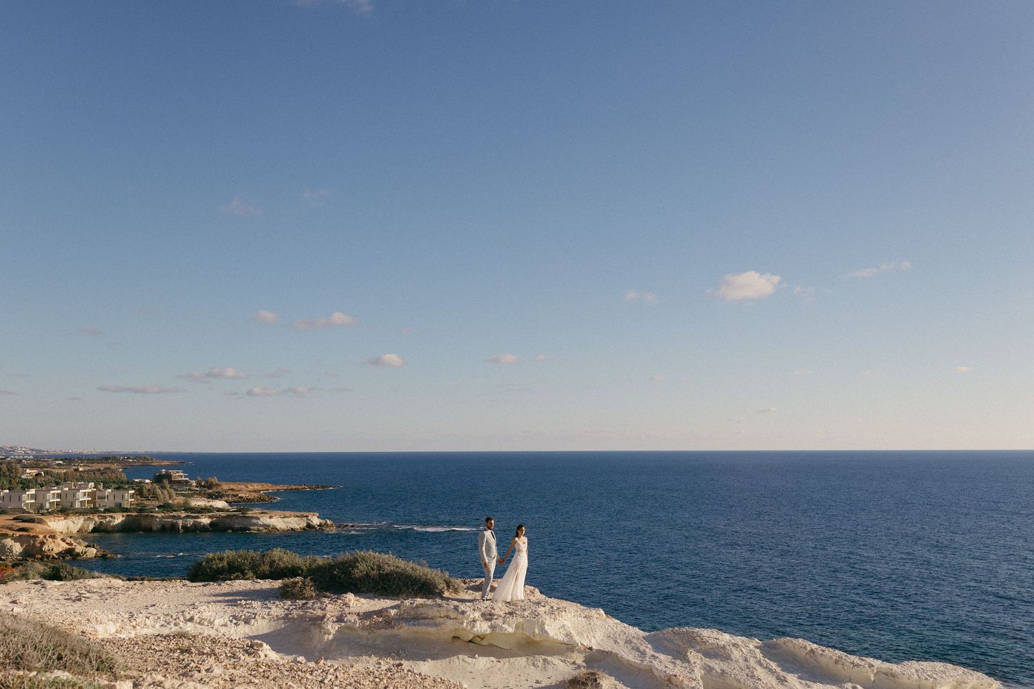 Bride and Groom posing on a cliff beautifully during their wedding portrait photoshoot.