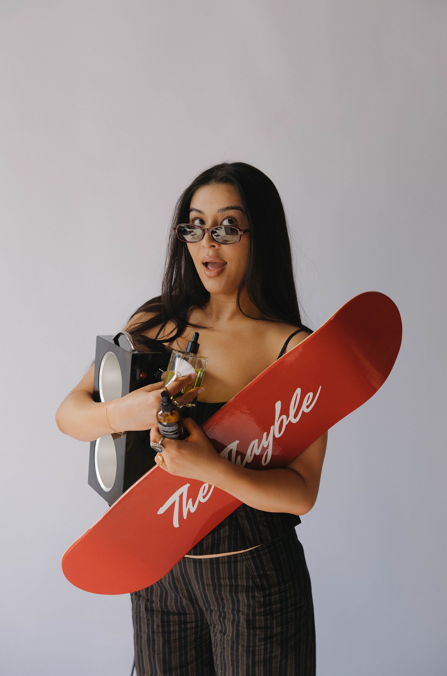 A series of photos showing someone in a striped dress holding up a red curved shape against a light gray background.